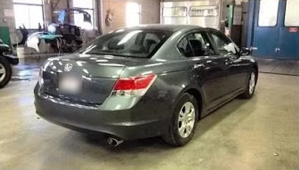The same grey sedan after repair and refinishing, panels straight and glossy